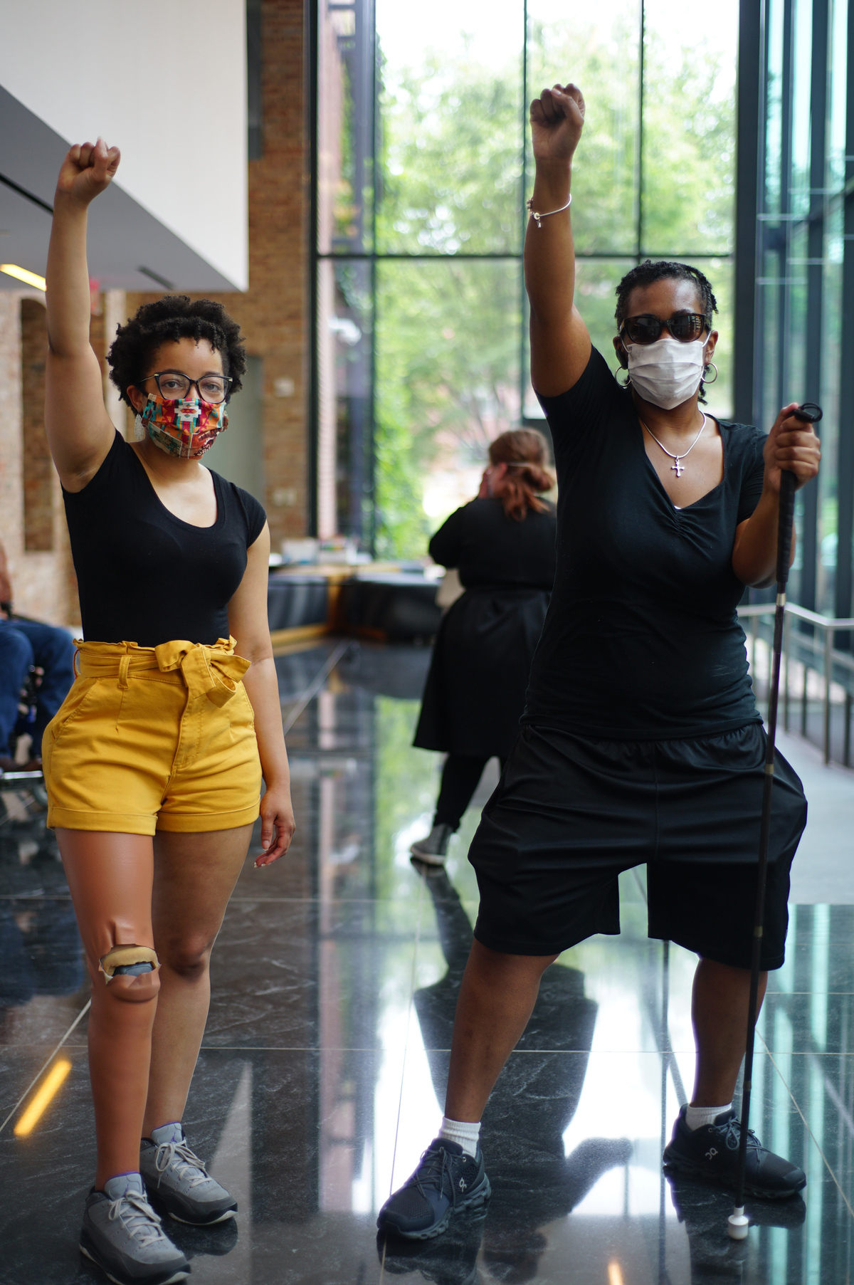 Photo of Keri Gray and Justice Shorter (two Black women). They both have their fist raised in the air.